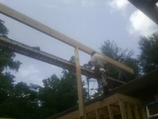 Carpenter setting a ridge beam over a new addition frame — Ice Dam Removal by Roofing Brothers in Diggs