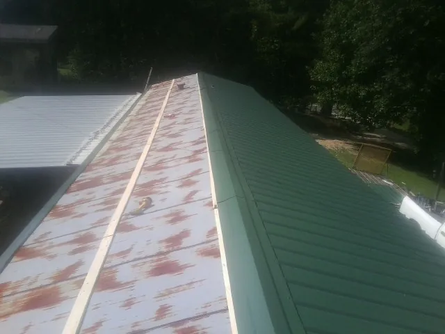 Old rusted panels beside newly installed green metal roofing — Wind Damage Roof Repair by Roofing Brothers in Diggs