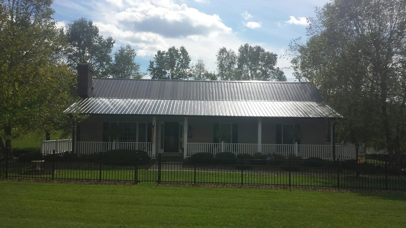 Gray metal roof on a brick ranch with a full width front porch — Gutter Guard Installation work by our crew in Diggs