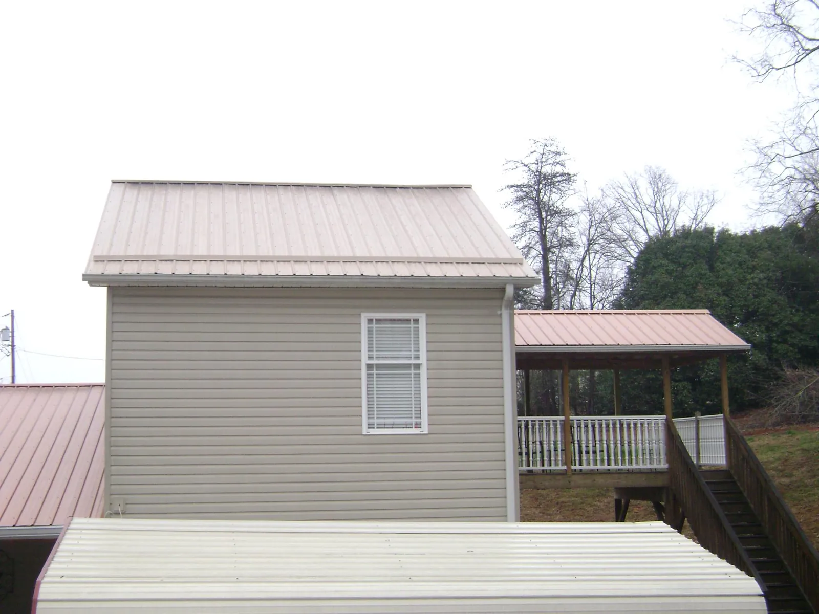Tan metal roofs on a two story addition and attached porch, from a Roof Replacement job in Diggs